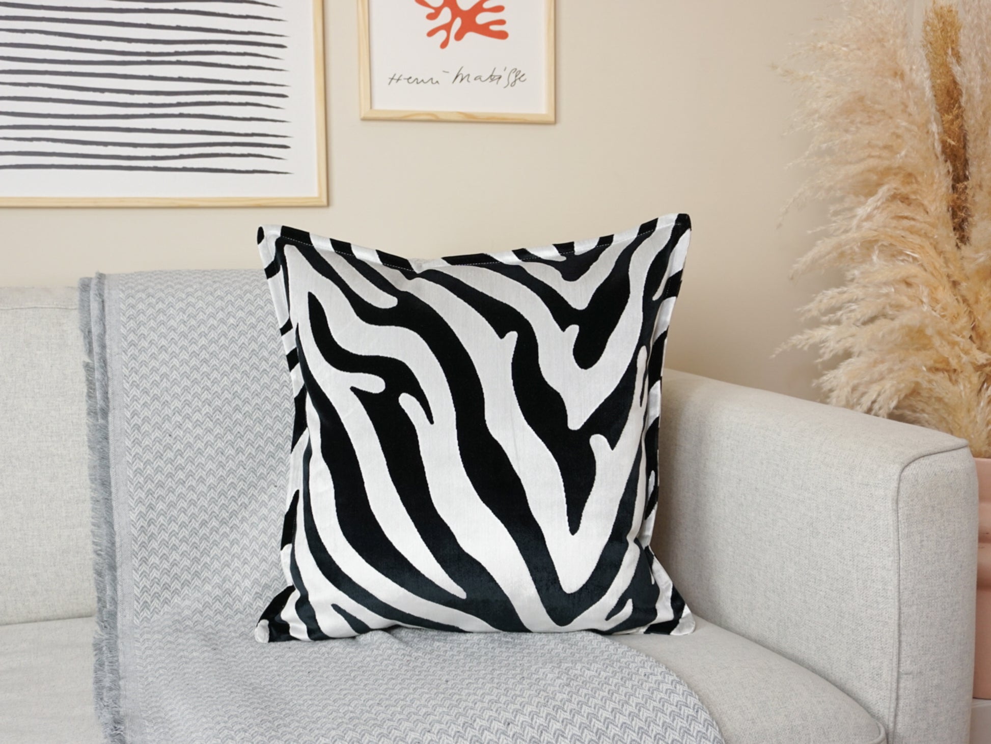 A cushion cover with a black and white zebra pattern, placed on a sofa in a living room setting.